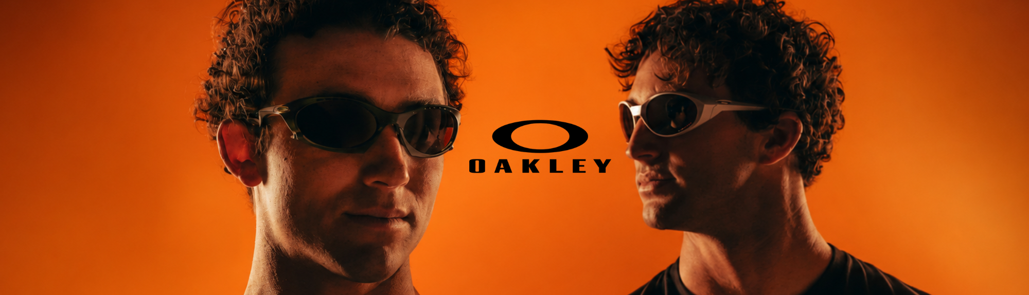 Two men wearing Oakley sunglasses posed against a vibrant orange background with the Oakley logo in the center.